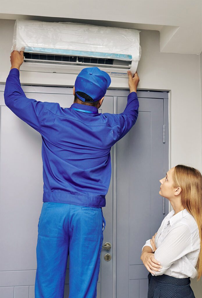 HVAC Worker fixes AC unit while property manager supervises