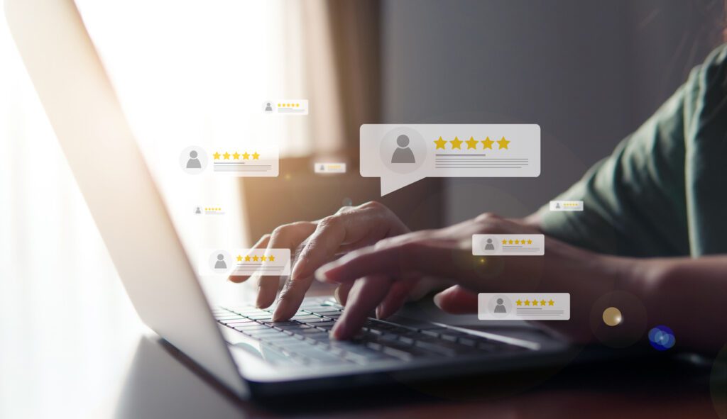 Close-up of hands typing on a laptop keyboard with overlaid icons of five-star customer reviews. The glowing review icons represent positive user feedback and satisfaction, emphasizing smart solutions for managing access control systems like RemoteLock for multifamily properties or vacation rentals.